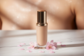 Premium luxury liquid foundation bottle on white marble with flower petals